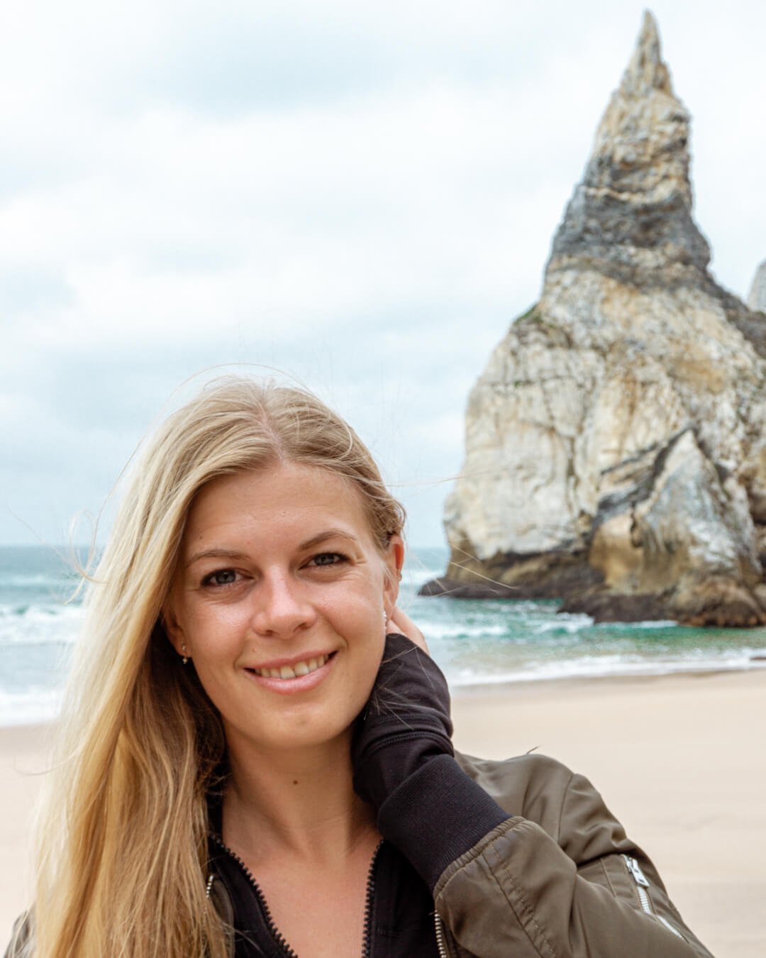 A girl standing in front of Praia da Ursa rock in Portugal.