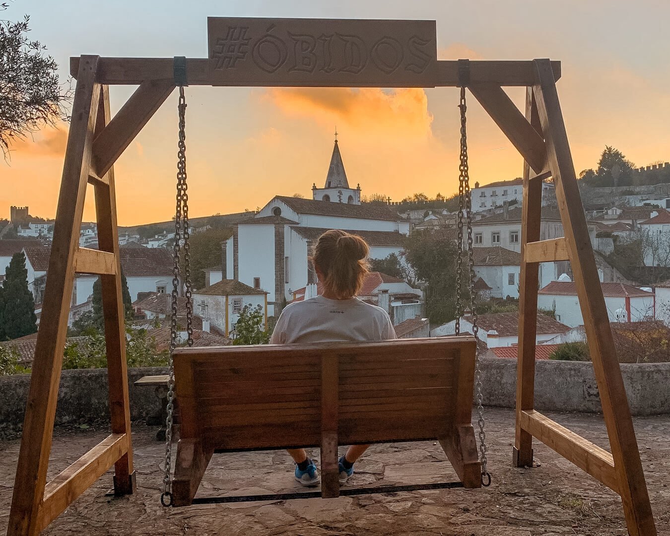 A man siitting in swing at Obidos Castle.
