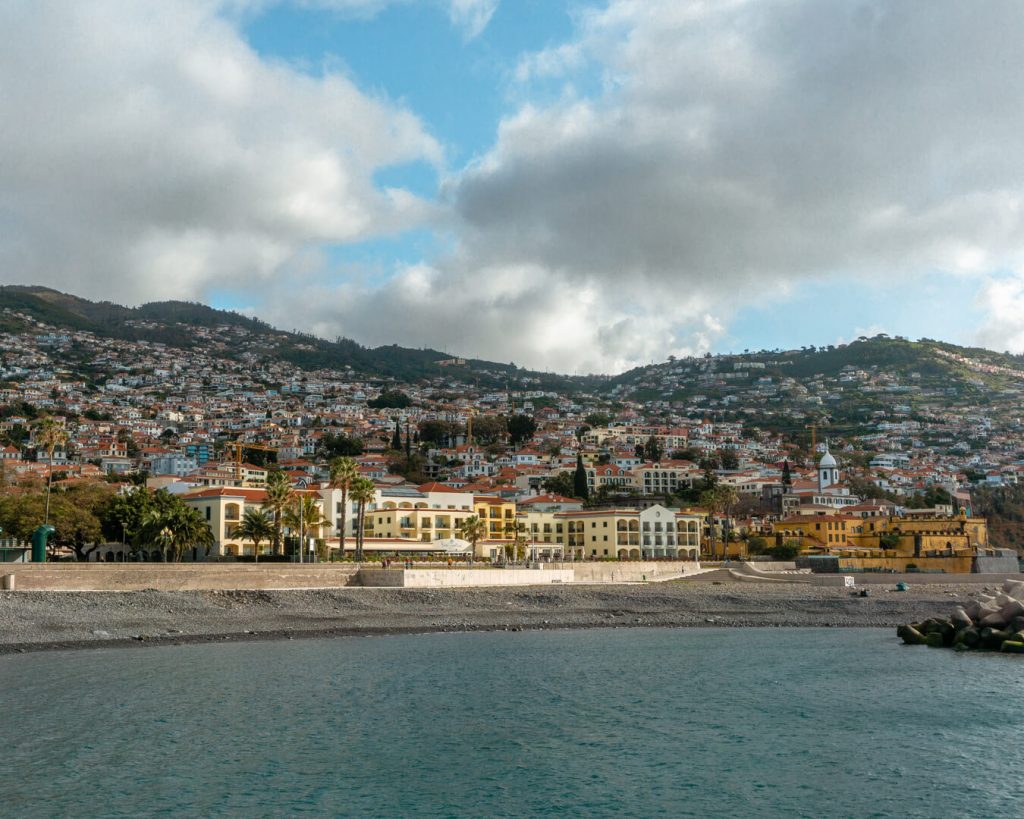 Pebble beach in Funchal with buildings in the background.