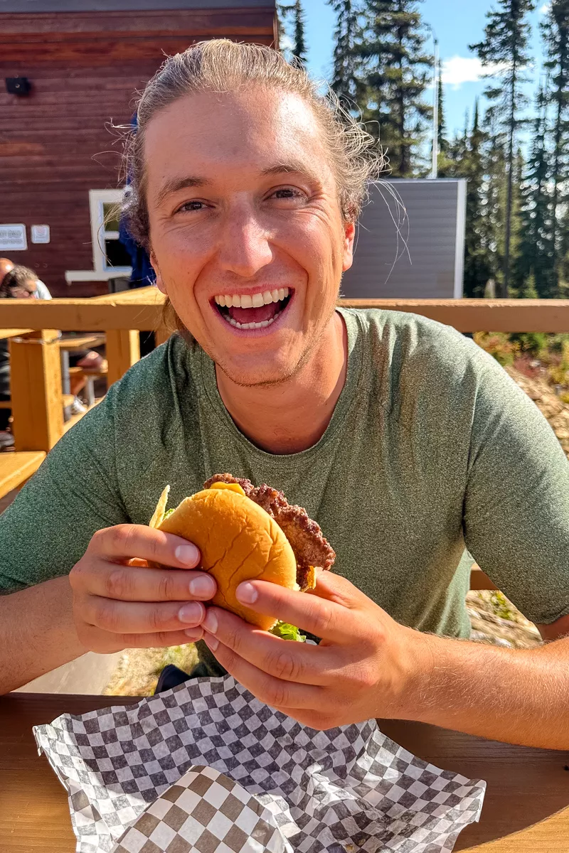 Dom eating a burger at the top of Mckenzie Outpost on Revelstoke Mountain Resort.