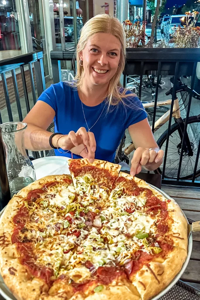 A girl taking a slice of a large pizza at Padrinos Pizzeria in Revelstoke