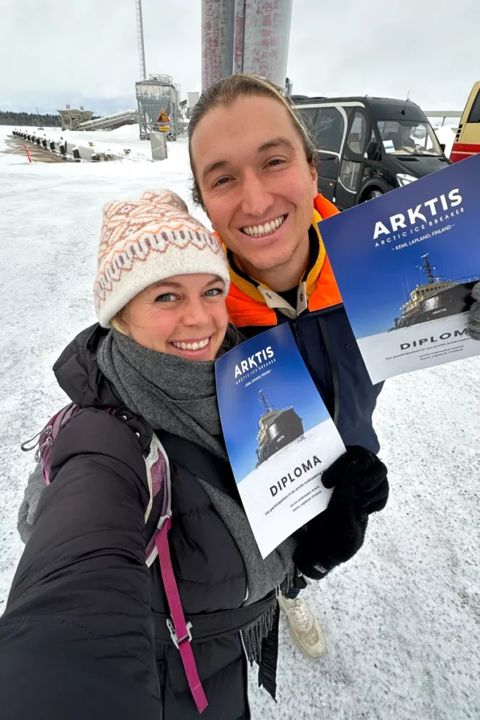 Smiling couple holding Arktis Icebreaker diplomas after completing the ice floating experience in Kemi, Lapland, Finland.