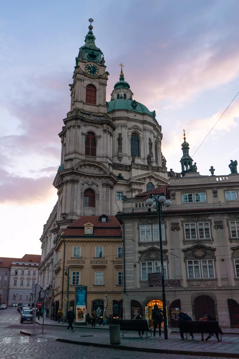 St. Nicholas Church in Prague’s Old Town at sunset with pastel sky in the background.