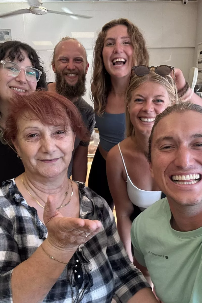 Selfie of a group of friends smiling at a bakery in Greece