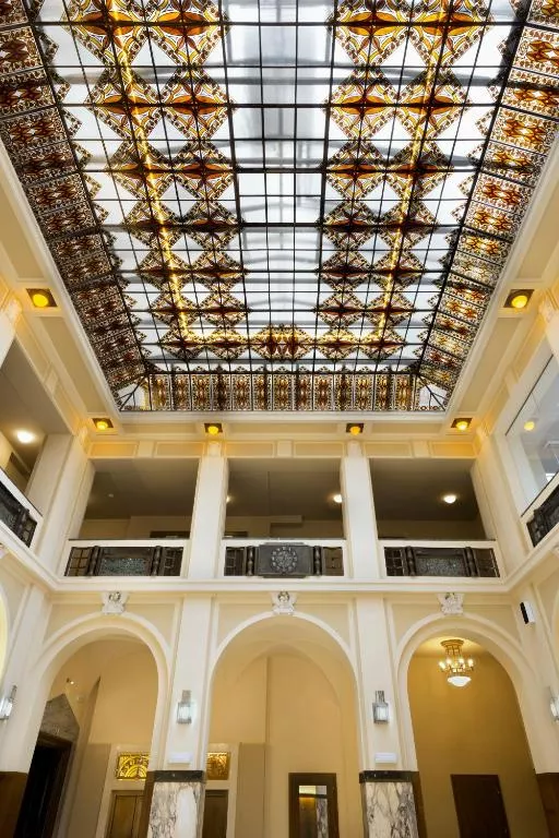 A grand interior space with two levels and a stained-glass ceiling.