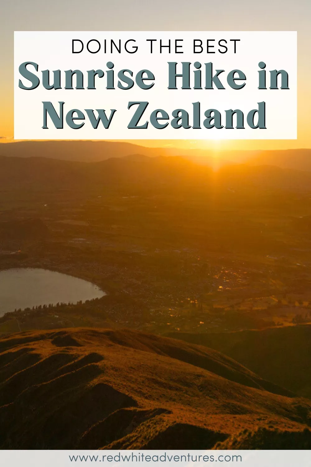 A sunrise view from Roys Peak looking down over Lake Wanaka and the town below, with rolling ridgelines in the foreground lit by golden morning light. Text overlay reads “Doing the best Sunrise Hike in New Zealand”.