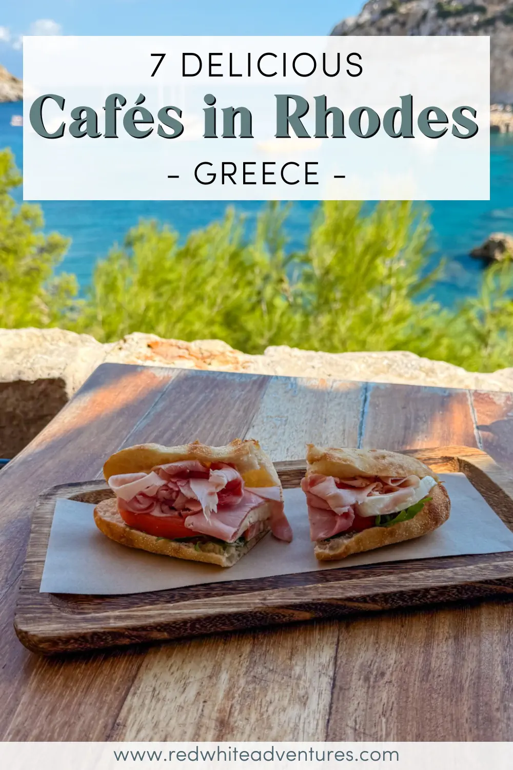 A fresh ham sandwich on ciabatta with tomato and lettuce sits on a wooden tray, overlooking the turquoise sea and lush greenery in Rhodes, Greece. The overlay text reads “7 Delicious Cafés in Rhodes – Greece.”