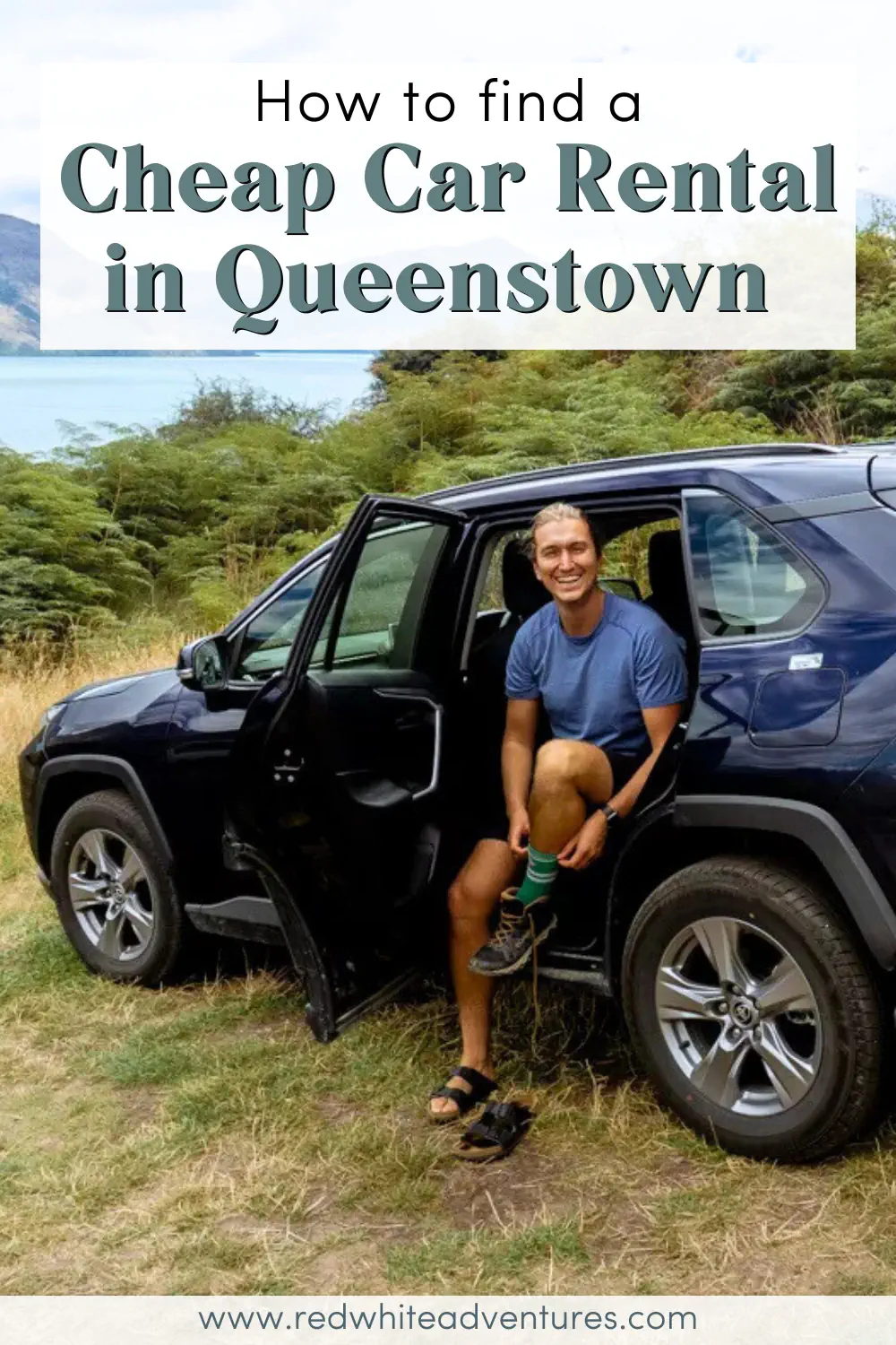 A smiling man sits in the open door of a dark blue rental car parked beside green bushes and mountain scenery near Queenstown, New Zealand. Text on the image reads: “How to find a Cheap Car Rental in Queenstown”.