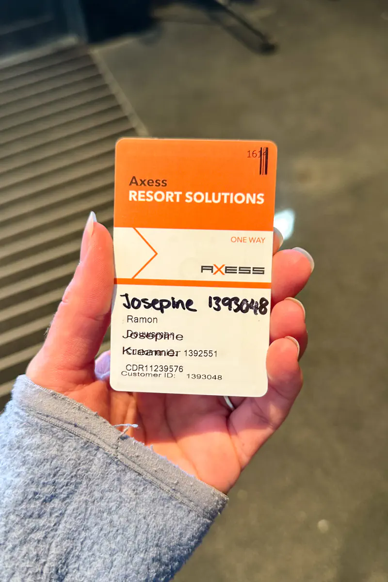 A hand holds a resort access card used for mountain activities. The image shows the card close up, emphasizing check-in and preparation before the adventure begins.