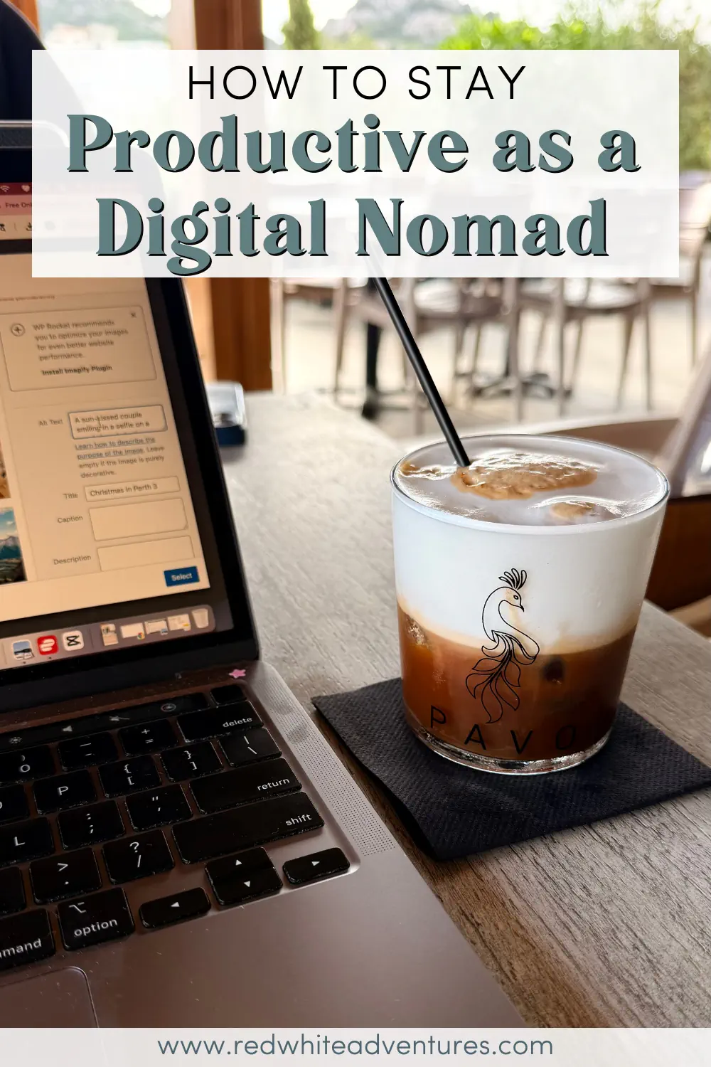 A laptop sits open on a café table beside an iced coffee with a foamy top. This image shows a typical remote work setup for digital nomads working from cafés.
