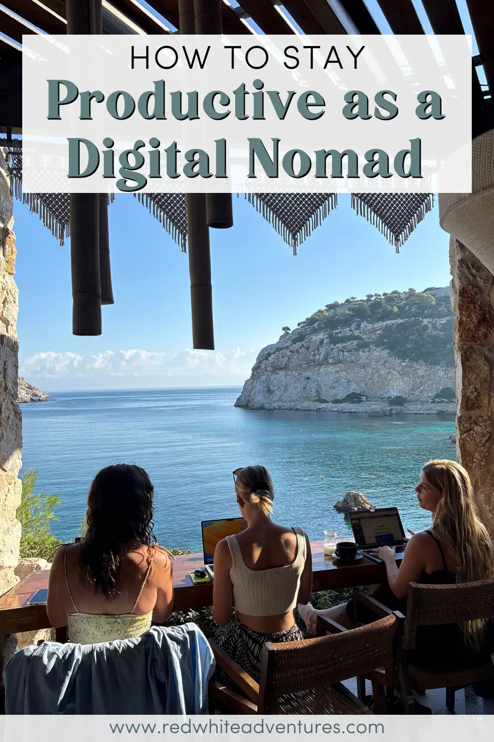 Three digital nomads work on their laptops at a wooden table overlooking a bright blue ocean and rocky cliffs. The scene highlights an inspiring coastal workspace ideal for remote productivity.