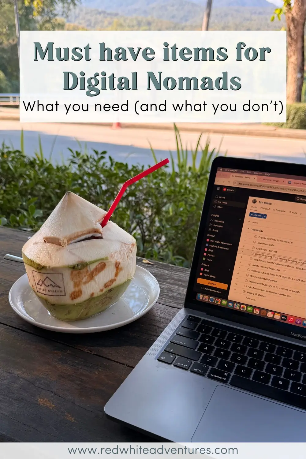 A fresh coconut with a red straw sits on a table next to an open laptop, with text reading “Must have items for Digital Nomads: What you need (and what you don’t).” The image captures a tropical remote work setup commonly associated with the digital nomad lifestyle.