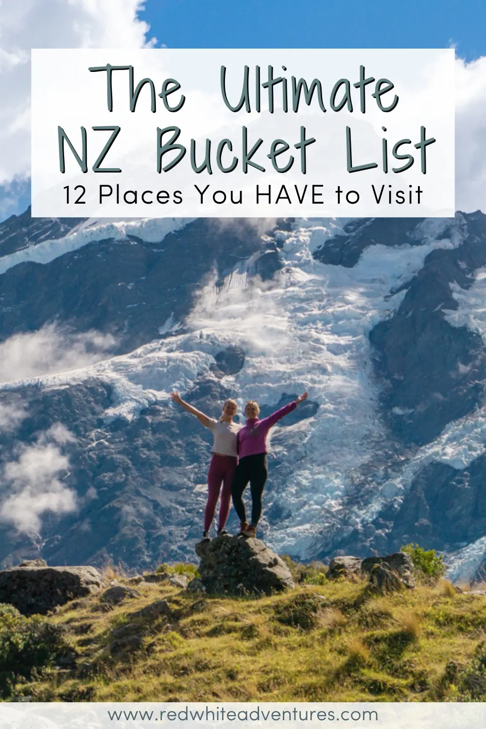 Two travellers stand on a rocky outcrop with arms raised in front of a towering glacier and rugged mountain under a blue sky. Text reads The Ultimate NZ Bucket List 12 Places You HAVE to Visit.