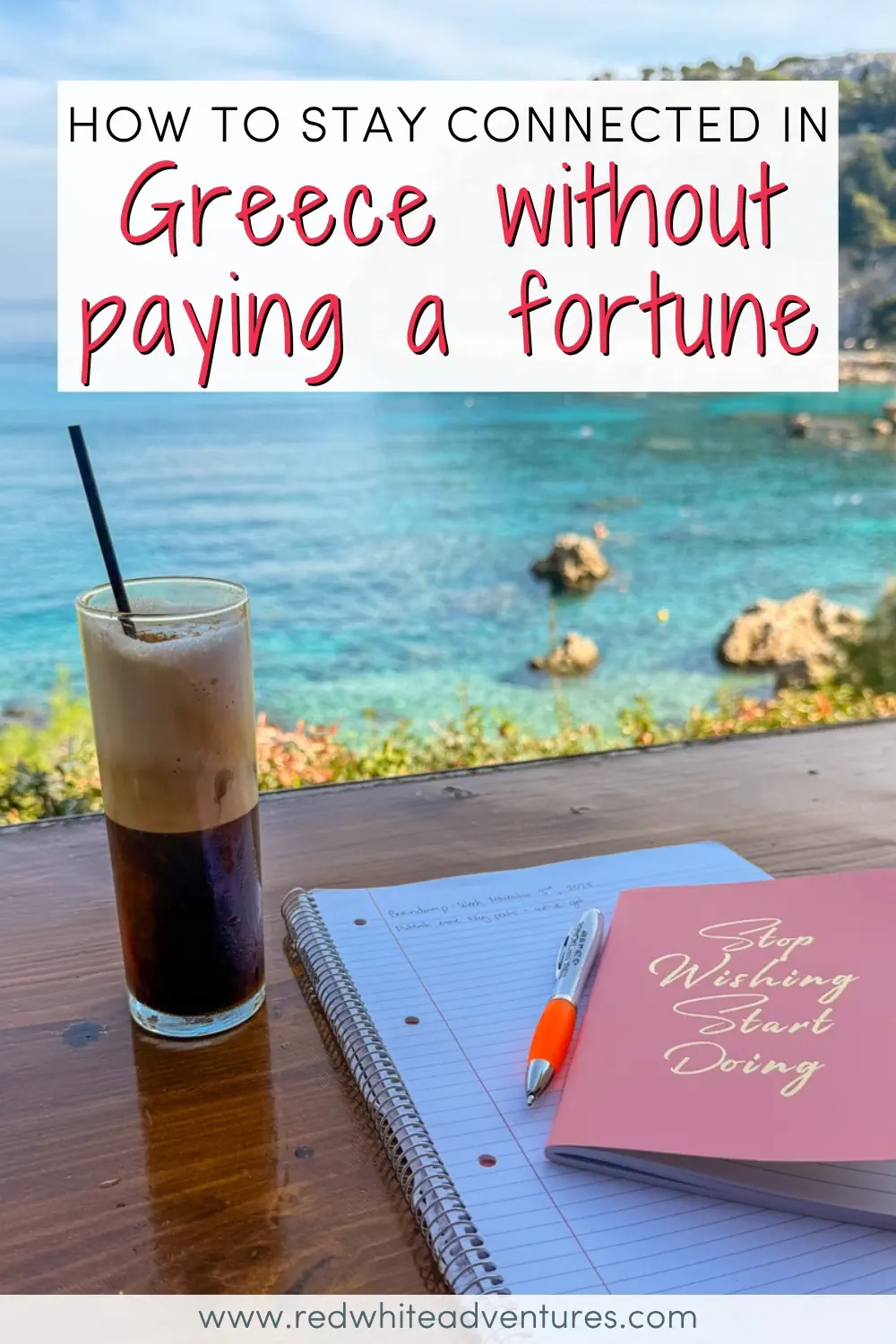 A Greek freddo cappuccino coffee and an open notebook sit on a wooden table overlooking a stunning turquoise cove with rocky outcrops and lush hillside vegetation. Text overlay reads "How to Stay Connected in Greece Without Paying a Fortune."