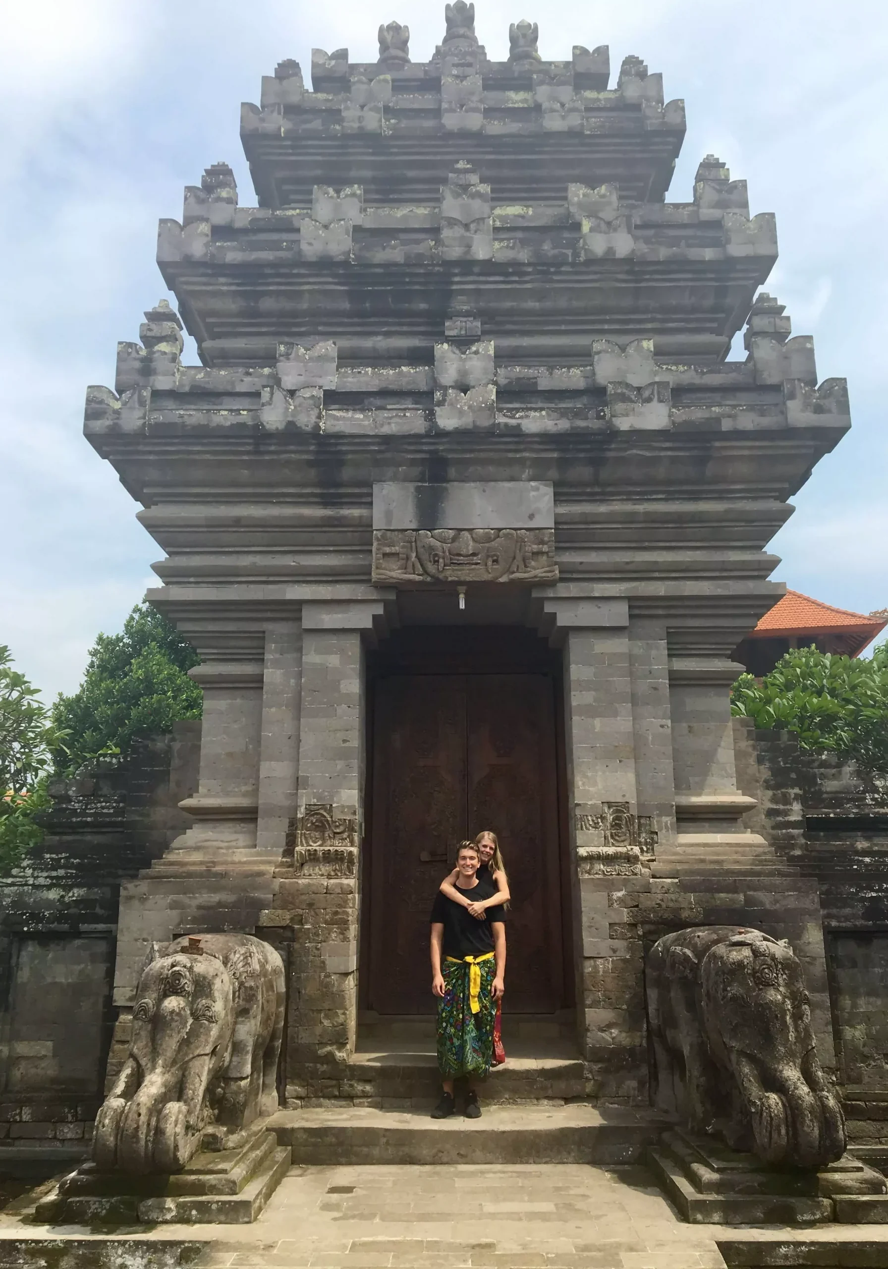 A couple standing in front of a temple in Bali.