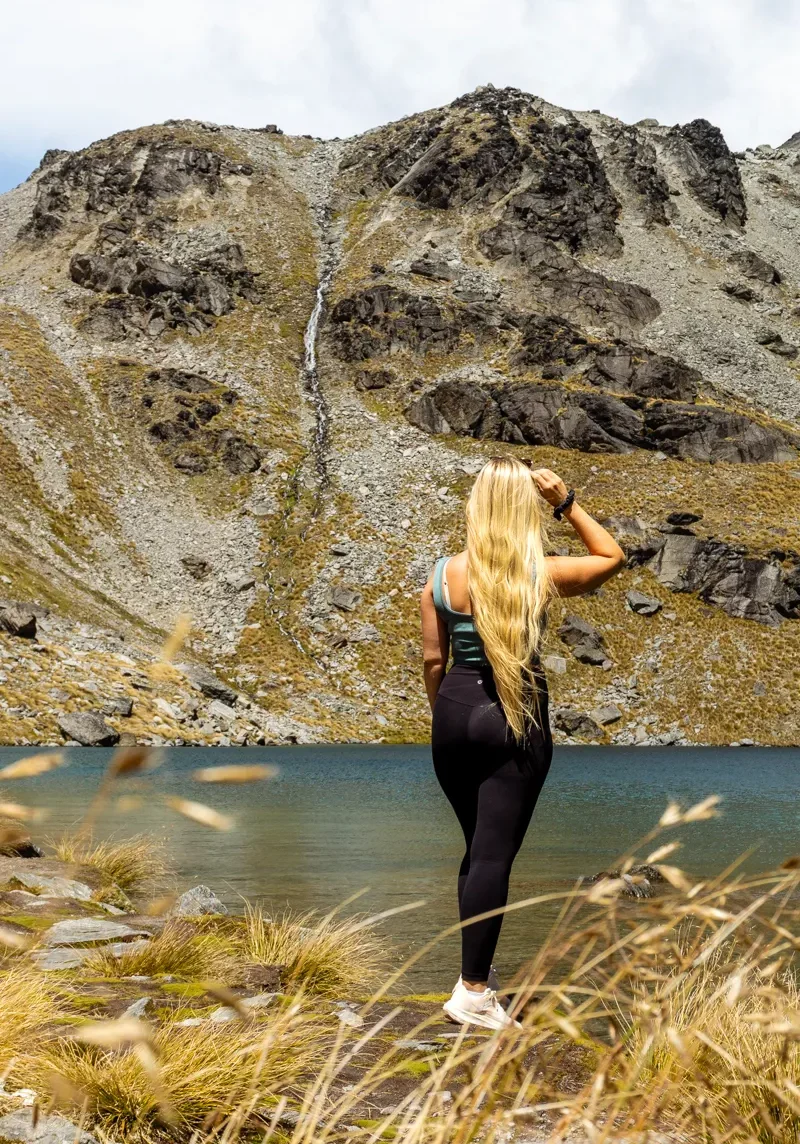 Jo taking in the view of a waterfall and Lake Alta up in the mountains near Queenstown.