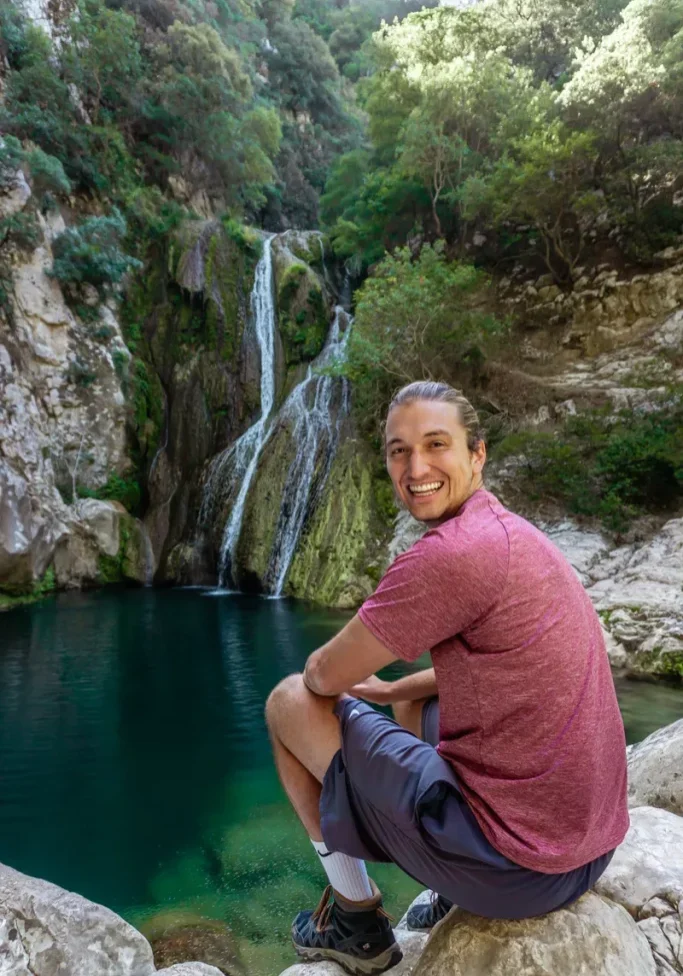 Dom smiling while enjoying the view of Polylimnio Waterfalls.