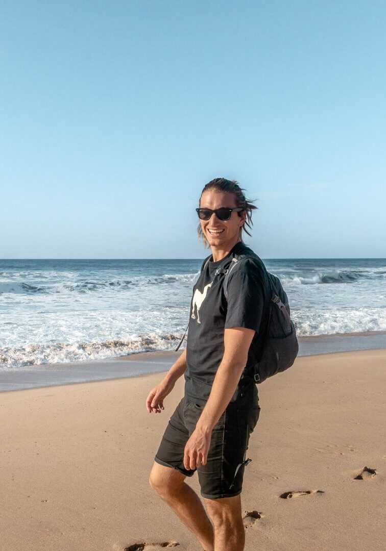 A guy walking on a beach in Ericeira