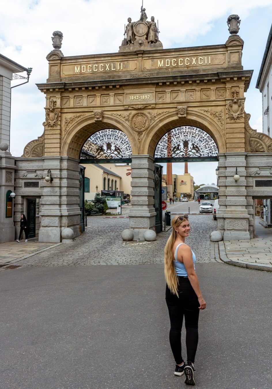 A girl standing in front of the Pilsner Urquell gate.