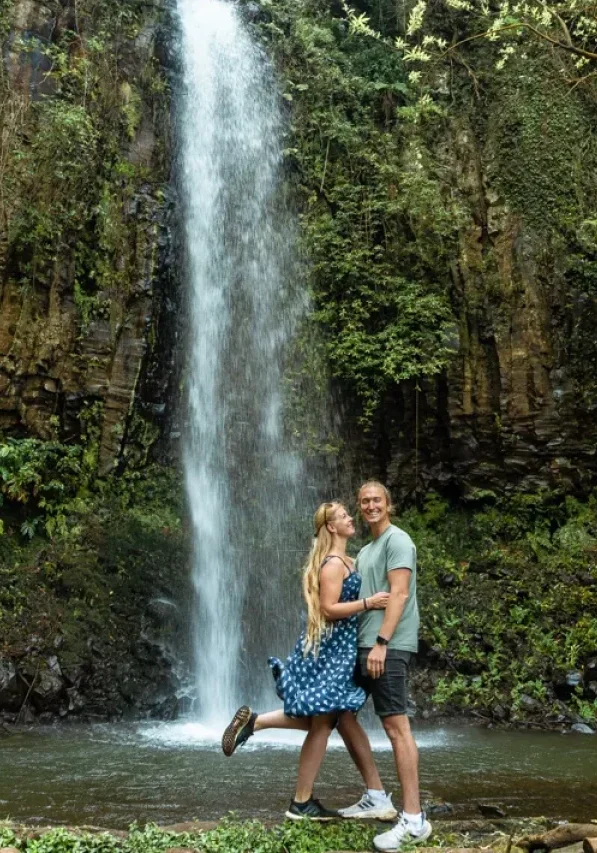 A couple standing in front of the Aguage Waterfall in Madeira.