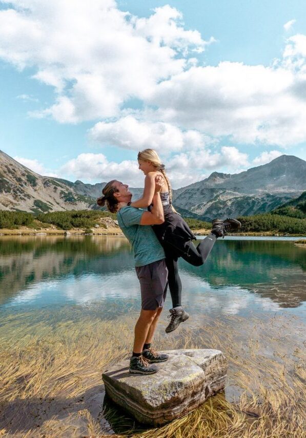 A couple standing on a rock at Lake Muratovo in the Pirin Mountains.