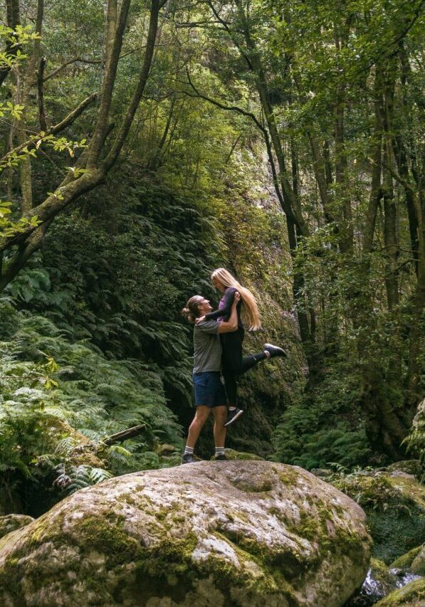 A couple standing on a rock at the end of Levada do Rei.